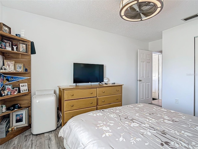 bedroom with light hardwood / wood-style floors and a textured ceiling