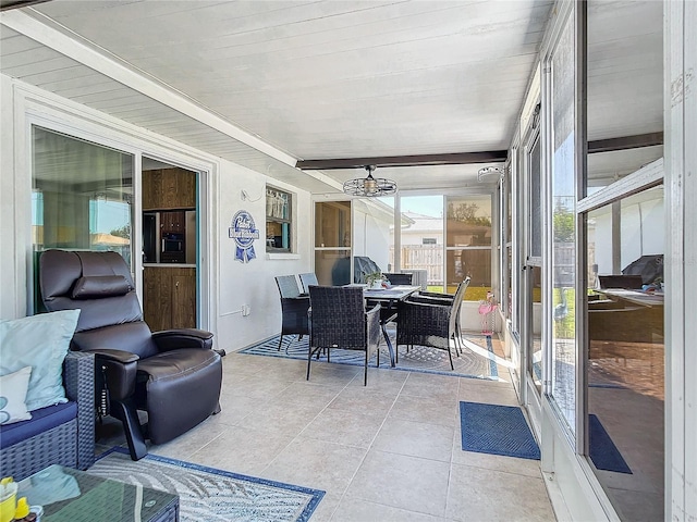 sunroom / solarium featuring beam ceiling and a chandelier