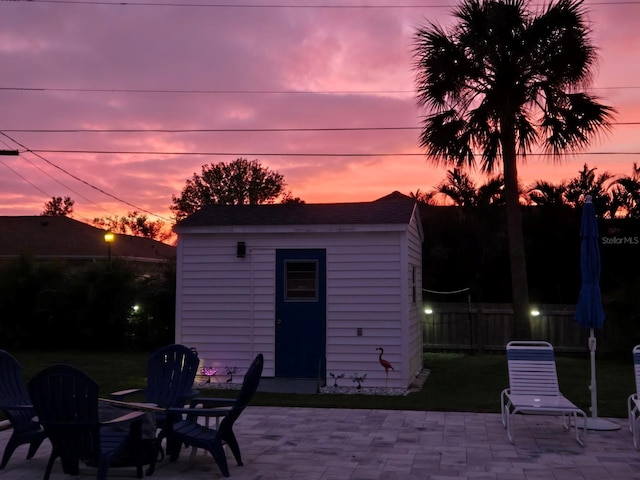 patio terrace at dusk featuring a storage shed