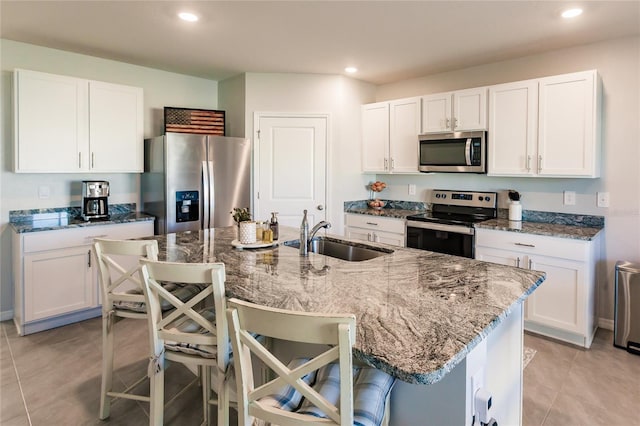 kitchen featuring sink, white cabinetry, stainless steel appliances, and a breakfast bar area