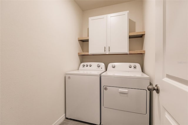 laundry area featuring washer and clothes dryer, light tile patterned flooring, and cabinets