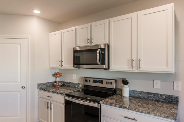 kitchen with white cabinets, stainless steel appliances, and dark stone countertops