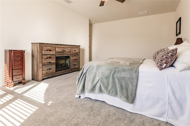 bedroom with ceiling fan, a fireplace, and light colored carpet