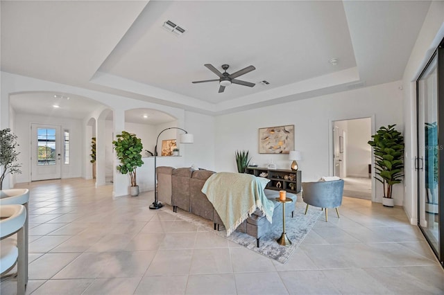 tiled living room featuring ceiling fan and a raised ceiling