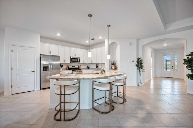 kitchen featuring light stone countertops, white cabinetry, stainless steel appliances, and a kitchen breakfast bar