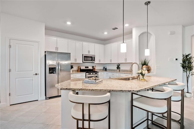 kitchen featuring white cabinetry, sink, hanging light fixtures, stainless steel appliances, and a breakfast bar