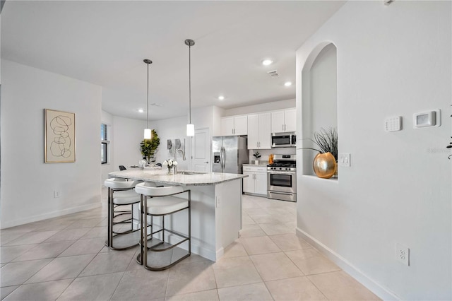 kitchen featuring sink, pendant lighting, a kitchen island with sink, white cabinets, and appliances with stainless steel finishes