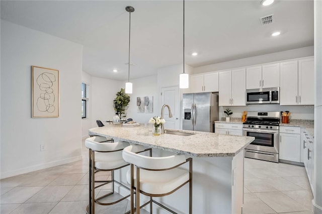 kitchen with sink, an island with sink, decorative light fixtures, and appliances with stainless steel finishes