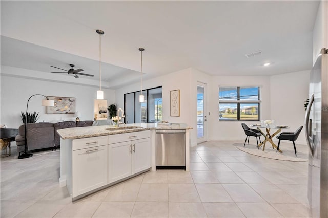 kitchen featuring sink, hanging light fixtures, light stone counters, white cabinets, and appliances with stainless steel finishes