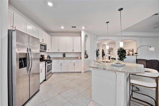 kitchen with sink, light stone counters, pendant lighting, white cabinets, and appliances with stainless steel finishes