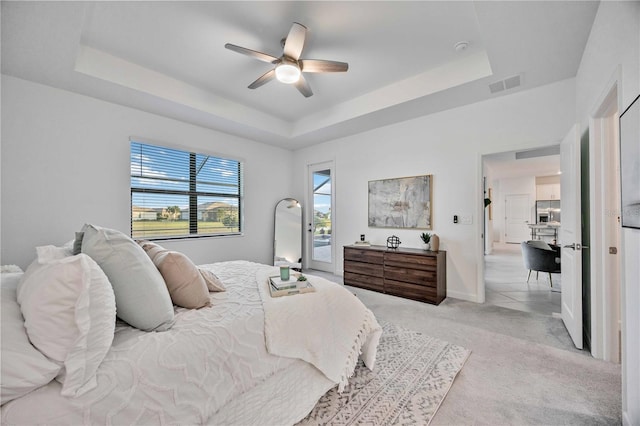 bedroom featuring access to outside, a raised ceiling, and ceiling fan