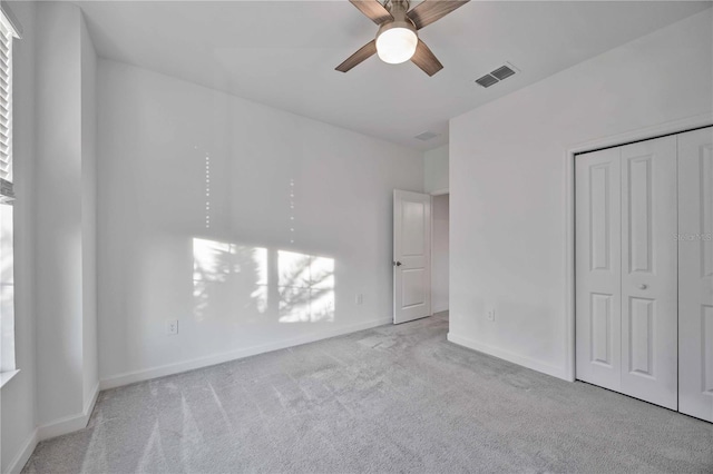 unfurnished bedroom featuring ceiling fan, a closet, and light colored carpet