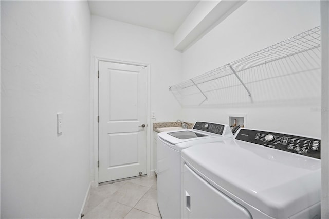 washroom featuring separate washer and dryer, sink, and light tile patterned floors