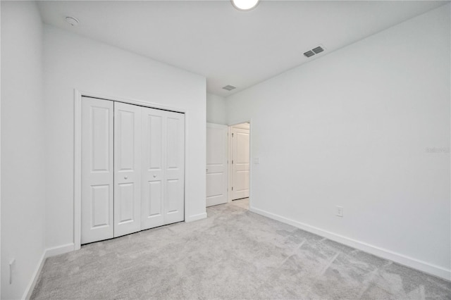 unfurnished bedroom featuring light carpet and a closet