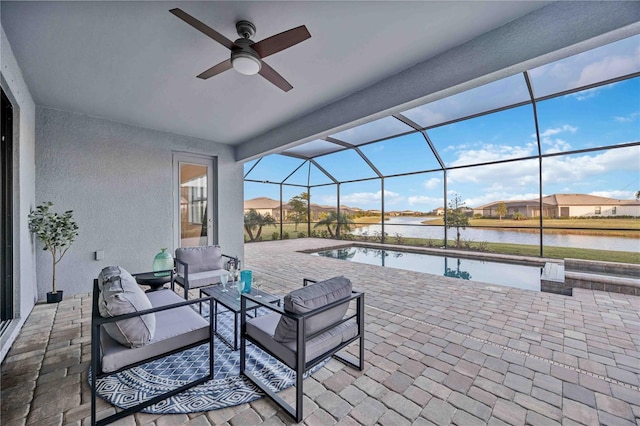 view of patio with a lanai, outdoor lounge area, ceiling fan, and a water view