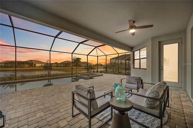 patio terrace at dusk featuring outdoor lounge area, ceiling fan, and a lanai