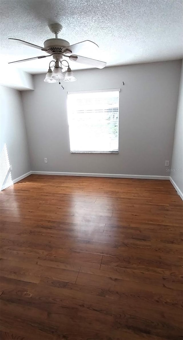 spare room with a textured ceiling, ceiling fan, and dark wood-type flooring