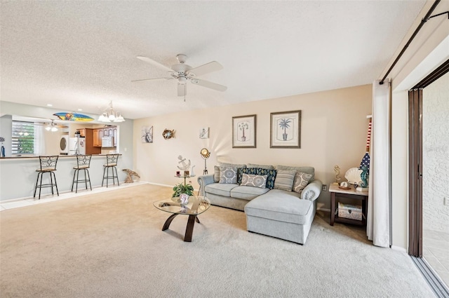 carpeted living room featuring ceiling fan with notable chandelier and a textured ceiling