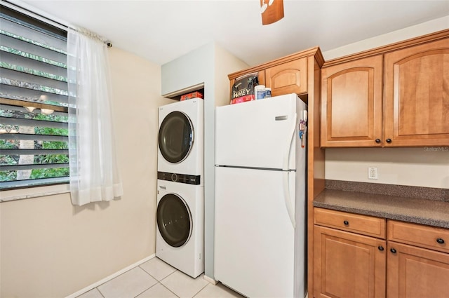 laundry area featuring stacked washer / drying machine and light tile patterned floors