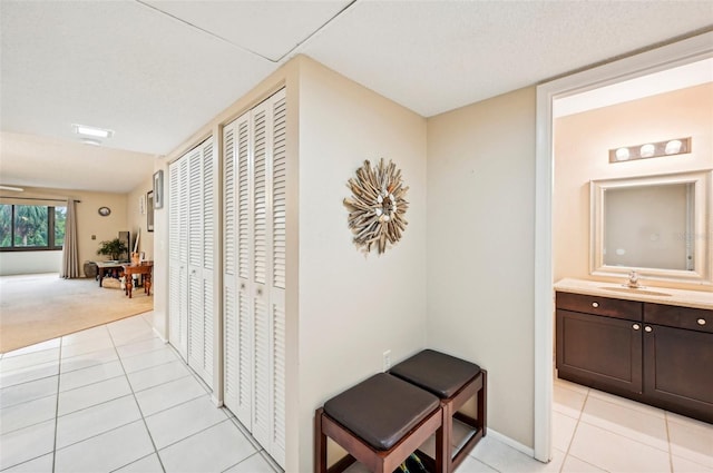 hallway with light tile patterned floors, a textured ceiling, and sink