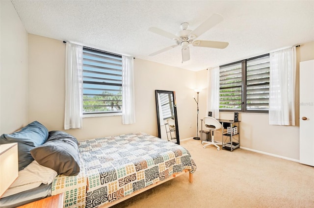 bedroom featuring multiple windows, ceiling fan, light carpet, and a textured ceiling