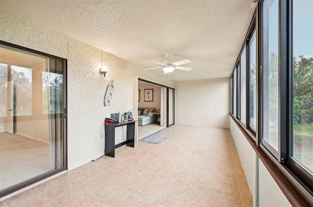 unfurnished sunroom featuring ceiling fan