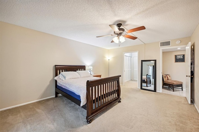 bedroom with ceiling fan, light colored carpet, and a textured ceiling