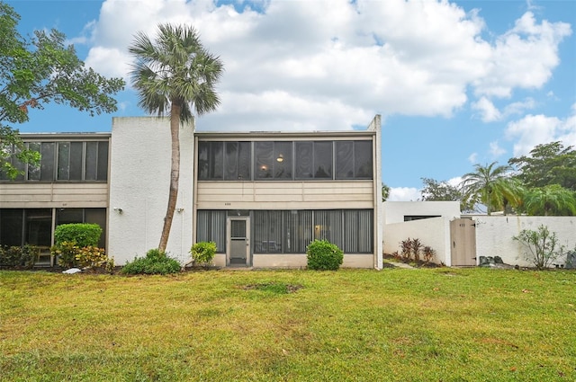 back of property featuring a lawn and a sunroom