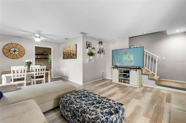 living room with hardwood / wood-style flooring, ceiling fan, and a textured ceiling