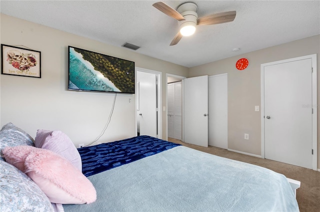 carpeted bedroom featuring a ceiling fan, visible vents, and a textured ceiling