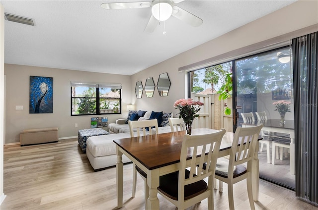 dining area with light wood finished floors, baseboards, visible vents, and ceiling fan