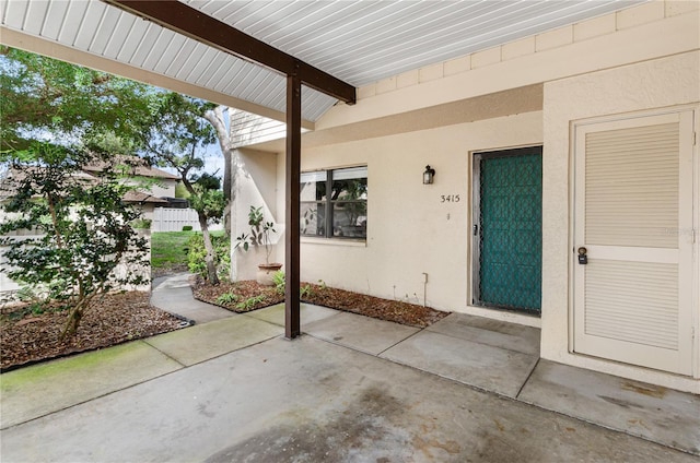 view of exterior entry featuring stucco siding and a patio