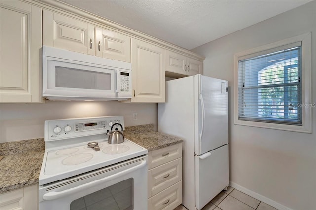 kitchen featuring light tile patterned flooring, light stone countertops, white cabinets, and white appliances