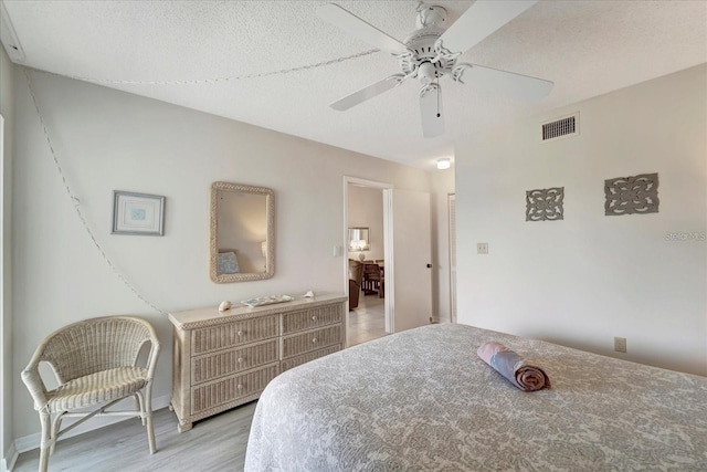 bedroom featuring ceiling fan, a textured ceiling, and light wood-type flooring