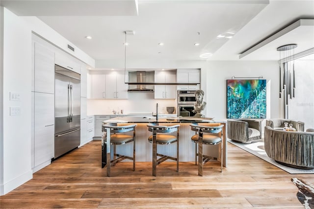 kitchen featuring a breakfast bar, stainless steel appliances, an island with sink, and light hardwood / wood-style flooring