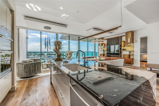 kitchen featuring dark stone counters, a spacious island, sink, light hardwood / wood-style flooring, and appliances with stainless steel finishes