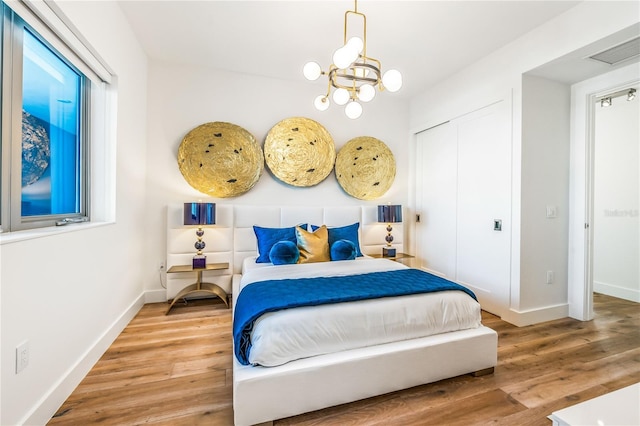 bedroom with hardwood / wood-style floors, a notable chandelier, and a closet