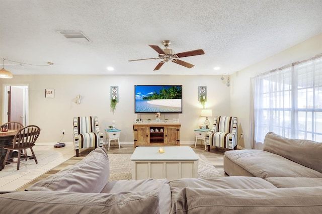 living room with light wood-type flooring, a textured ceiling, and ceiling fan