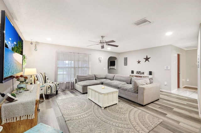 living room with ceiling fan, light hardwood / wood-style flooring, and a textured ceiling