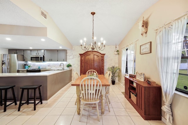 dining room with sink, light tile patterned floors, lofted ceiling, and an inviting chandelier