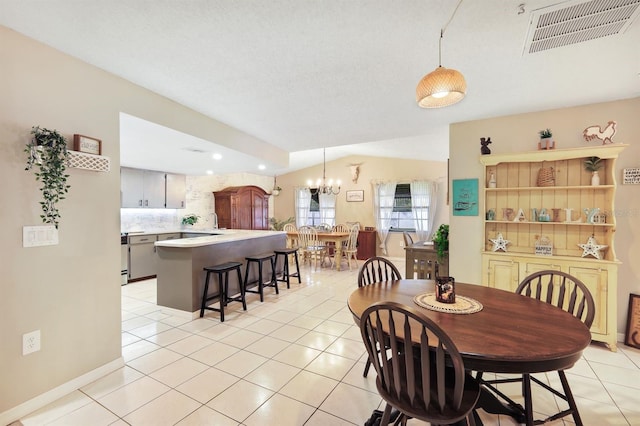 dining room featuring light tile patterned floors, vaulted ceiling, an inviting chandelier, and sink