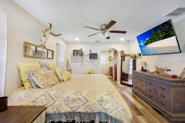 bedroom with ceiling fan, light hardwood / wood-style floors, and a textured ceiling