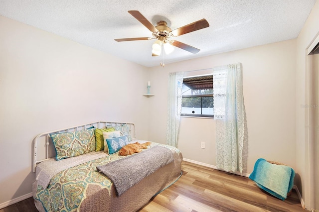 bedroom featuring ceiling fan, a textured ceiling, and light wood-type flooring