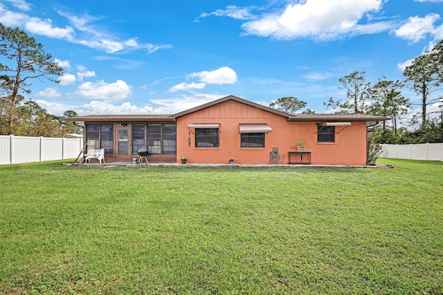 rear view of property with a sunroom and a yard