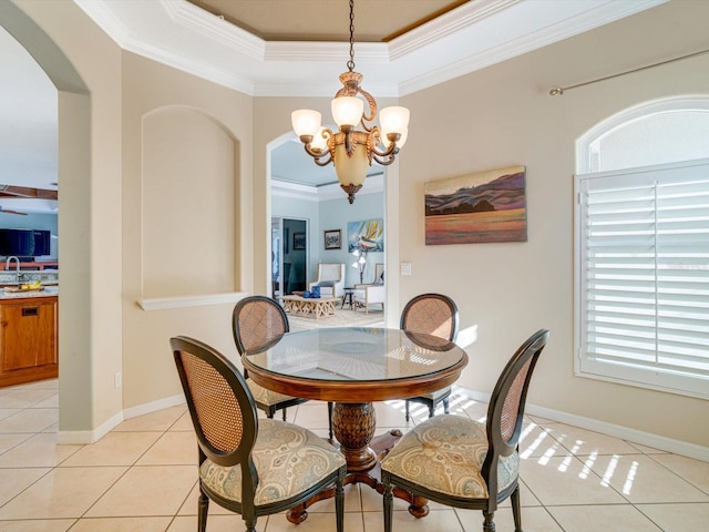 tiled dining area featuring a raised ceiling, ornamental molding, and a chandelier