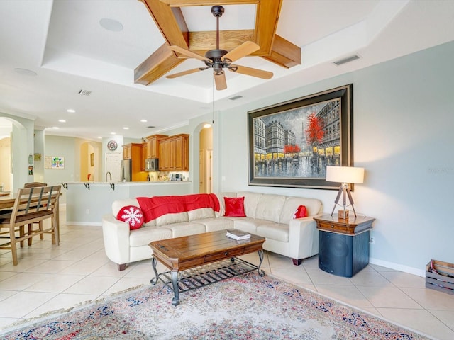 living room with ceiling fan, light tile patterned flooring, beam ceiling, and a tray ceiling