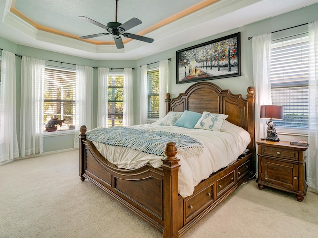 carpeted bedroom with a tray ceiling, ceiling fan, and ornamental molding