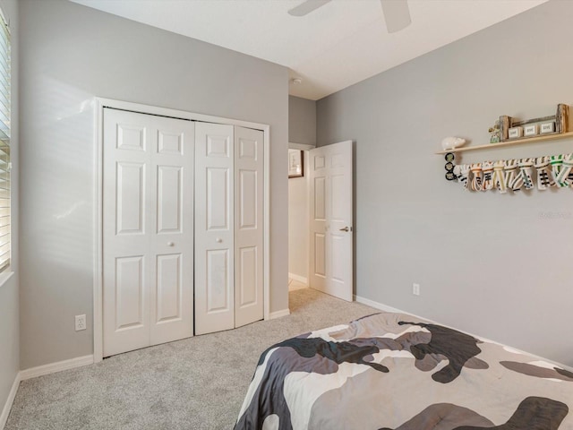 bedroom with multiple windows, ceiling fan, a closet, and light colored carpet