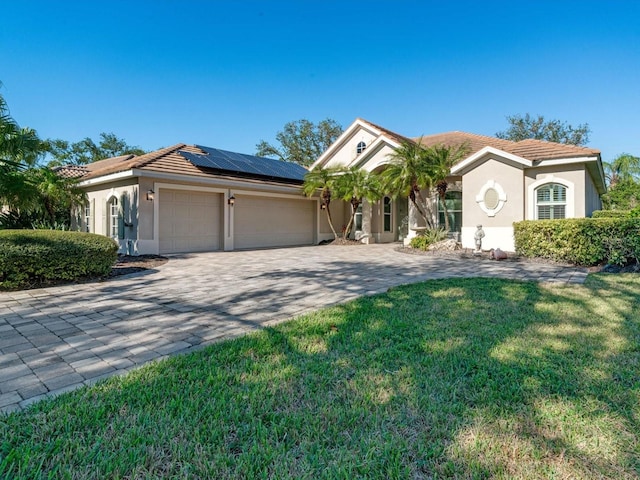 mediterranean / spanish-style house featuring solar panels, a garage, and a front lawn