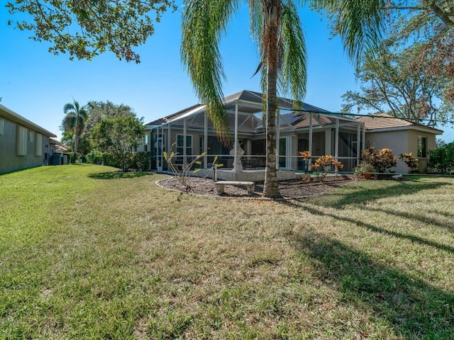 rear view of house featuring a lawn and glass enclosure